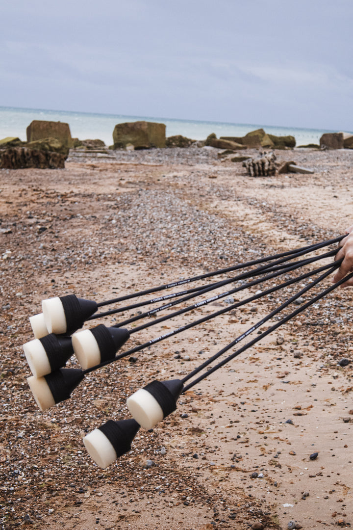 Set of black and white foam headed arrows for larp and cosplay held on a beach with rocks and water in the background