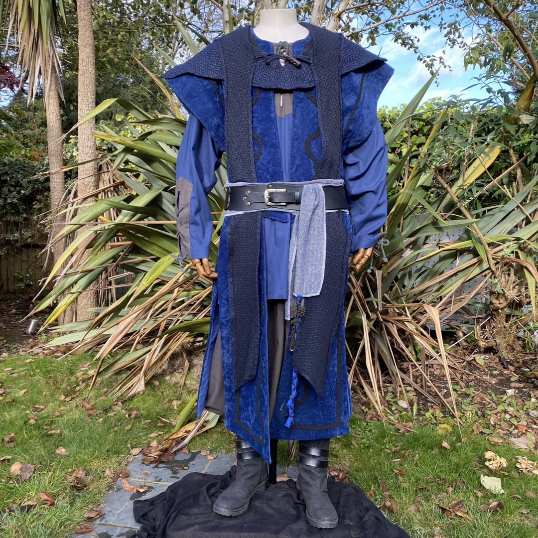 Medieval LARP costume front view, featuring a blue suede-effect panel waistcoat, wool hood, two-tone cotton tunic and wool sash. For Renaissance Faire and historical roleplay events.