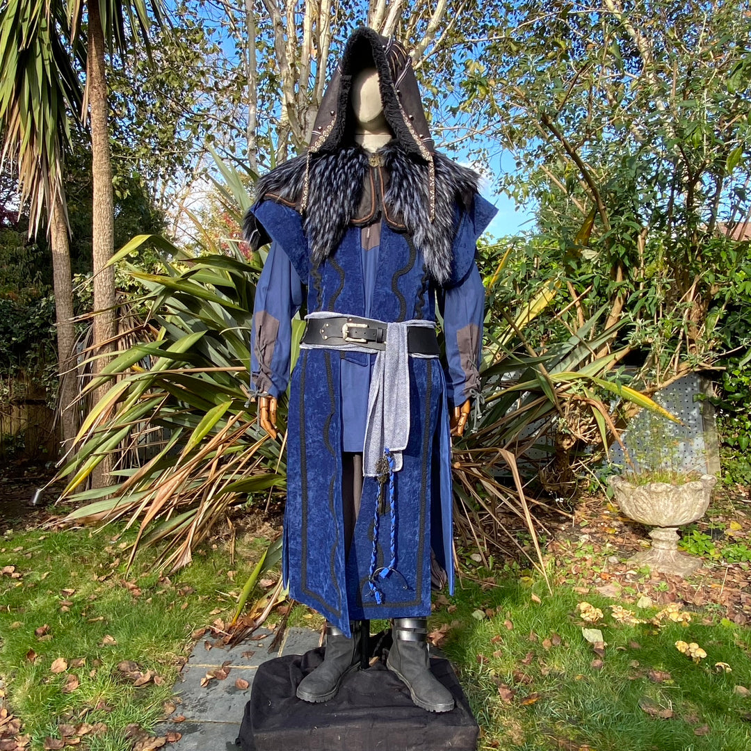 Medieval LARP costume front view, featuring a blue suede-effect panel waistcoat, black faux-leather hood, two-tone cotton tunic and wool sash. For Renaissance Faire and historical roleplay events.