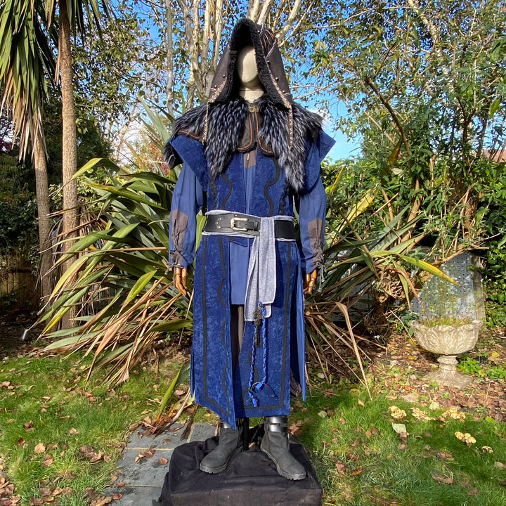 Medieval LARP costume front view, featuring a blue suede-effect panel waistcoat, black faux-leather hood, two-tone cotton tunic and wool sash. For Renaissance Faire and historical roleplay events.