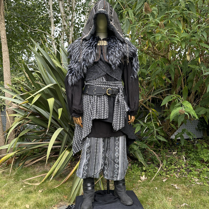 Medieval LARP costume front view, includes faux leather hood, black and white waistcoat with asymmetrical front panel and matching sash, wool hood, shirt, trousers and leather belt for roleplay events.
