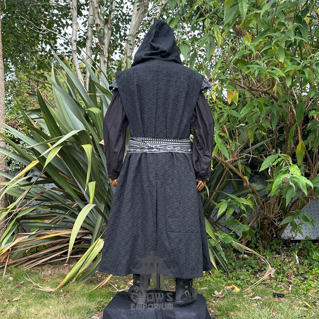 Medieval LARP costume back view featuring black sleeveless robe, hood, shirt, trousers, and sash. For Renaissance Faire and historical roleplay events.