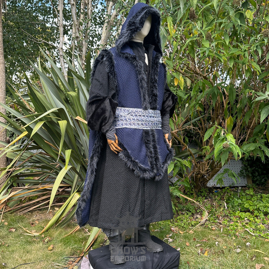 Medieval LARP costume side view, featuring a blue faux fur trim hooded cape, black high collared robe, and sash. For Renaissance Faire and historical roleplay events.