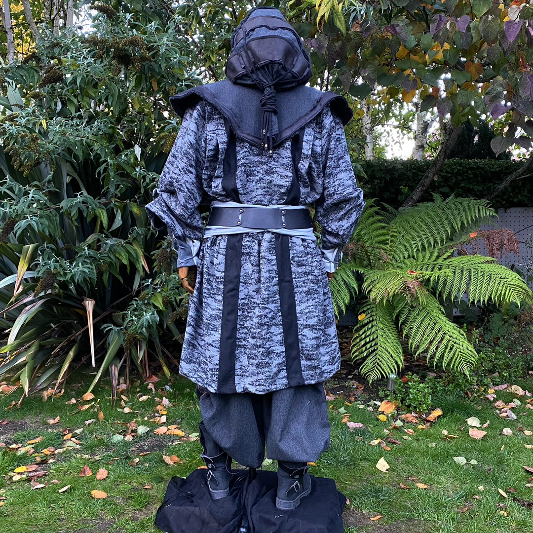 Medieval LARP costume back view, featuring faux leather hood and waistcoat, grey and black hooded robe, and a sash. For Renaissance Faire and historical roleplay events.