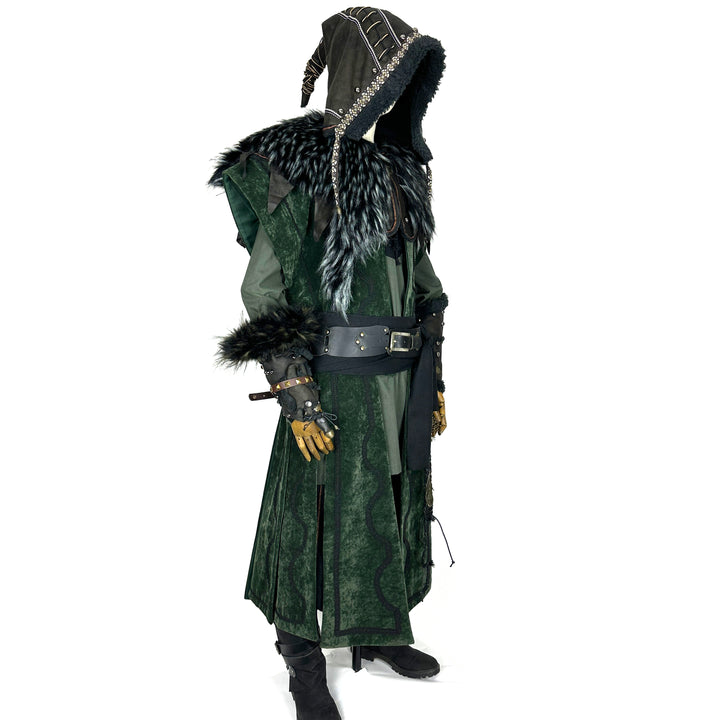 Side view of a medieval LARP costume, featuring a faux leather hood and vambraces, long green suede-effect waistcoat, shirt, pants, woolen sash and necklace. For Renaissance Faire and roleplay events.