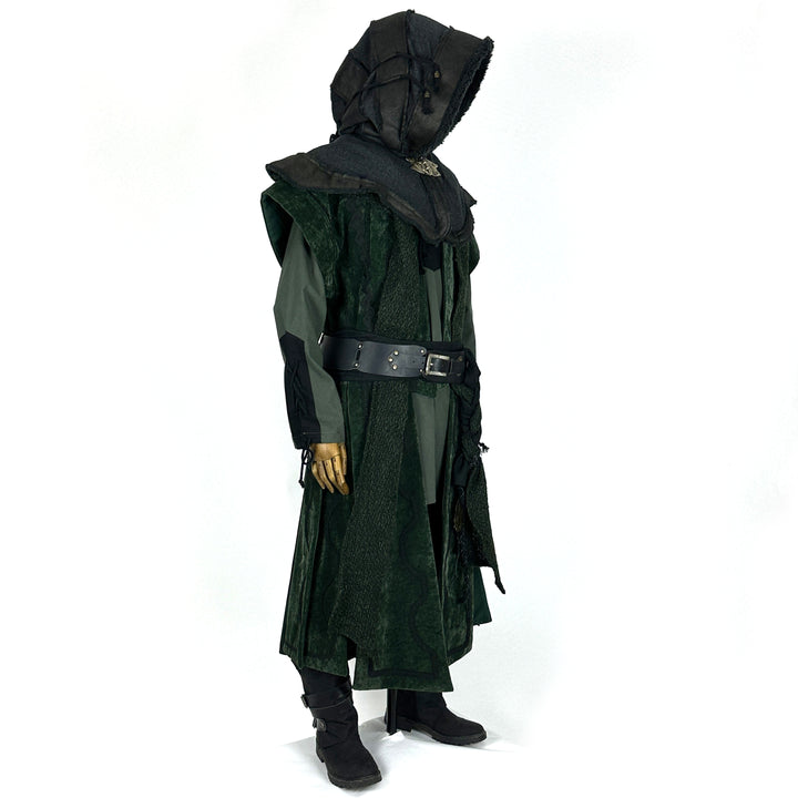 Side view of a medieval LARP costume, featuring a long green suede-effect waistcoat, leather and wool layered hood, shirt, pants, woolen sash and necklace. For Renaissance Faire and roleplay events.