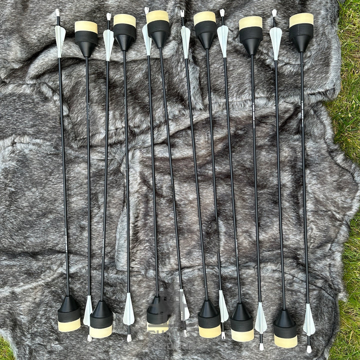 Set of black arrows with yellow nocks on a camouflage-patterned fabric background