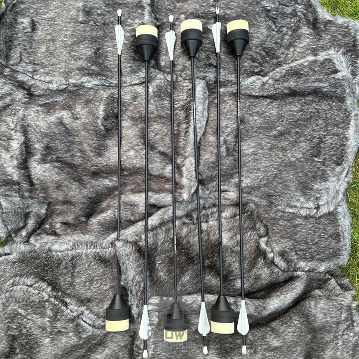 Set of six black and white archery nocks on a camouflage-patterned background