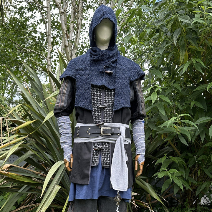Medieval LARP costume front view, featuring a black and grey wool jacket with ornate panels, a wool hood, arm wraps, and a sash. For Renaissance Faire and historical roleplay events.