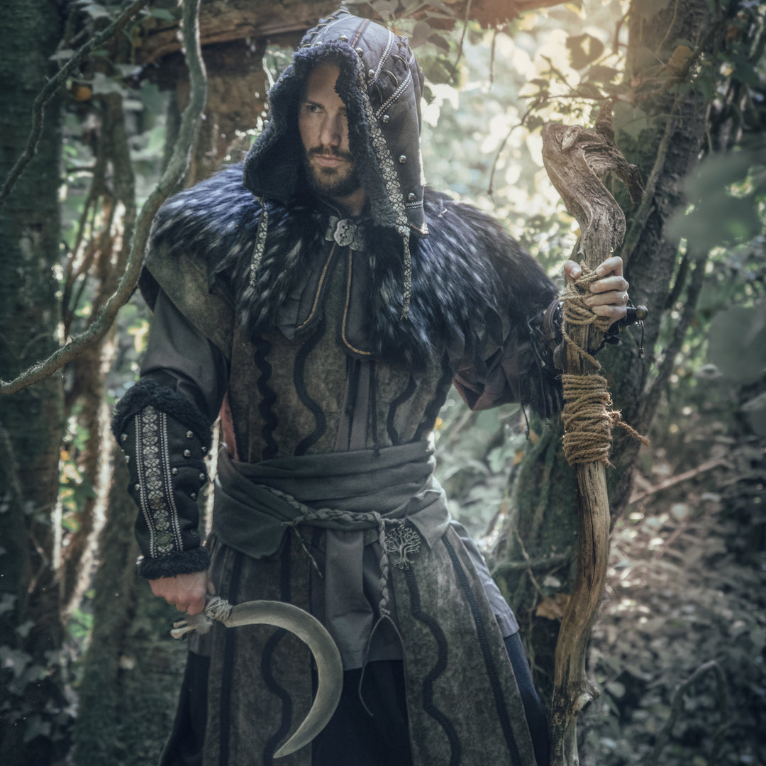 Front view of a man wearing a medieval LARP costume, featuring a faux leather hood, long green suede-effect waistcoat, shirt, pants, woolen sash and necklace. For Renaissance Faire and roleplay events.