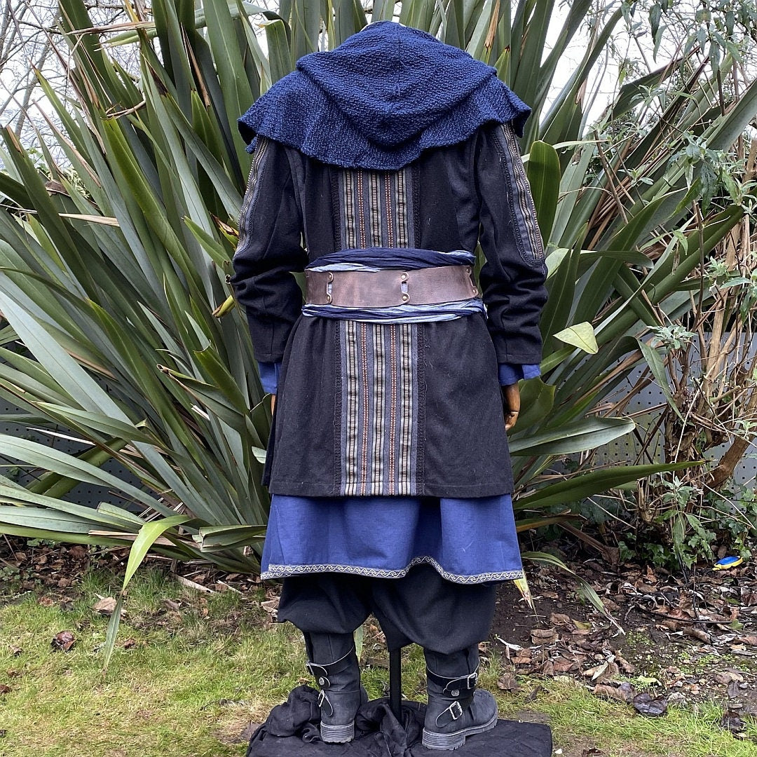 Medieval LARP costume back view, featuring a black and grey wool jacket, a wool hood, tunic, pants, sash and necklace. For Renaissance Faire and historical roleplay events.