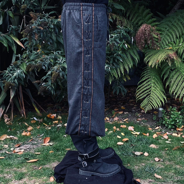 Side view of grey wool pants with wide decorative trim and cross-lace detailing