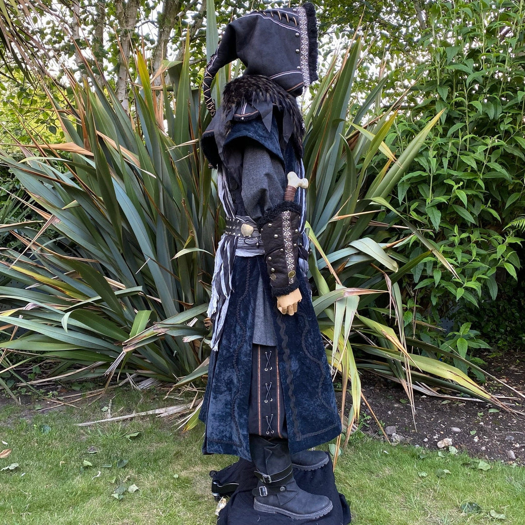 Medieval LARP costume side view featuring waistcoat, shirt, hood, vambraces, trousers, and accessories. For Renaissance Faire and historical roleplay events.