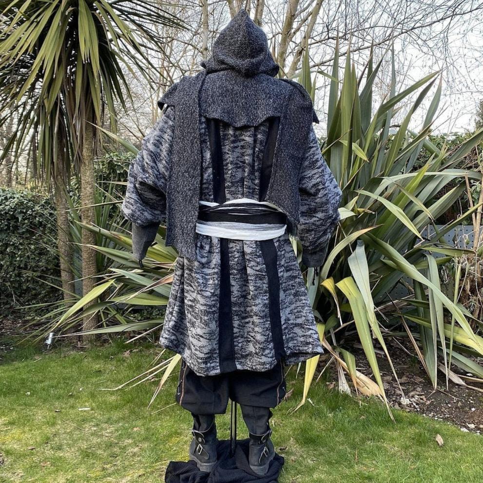 Medieval LARP costume back view, featuring grey and black hooded robe, wool hood, shirt and trousers. For Renaissance Faire and historical roleplay events.