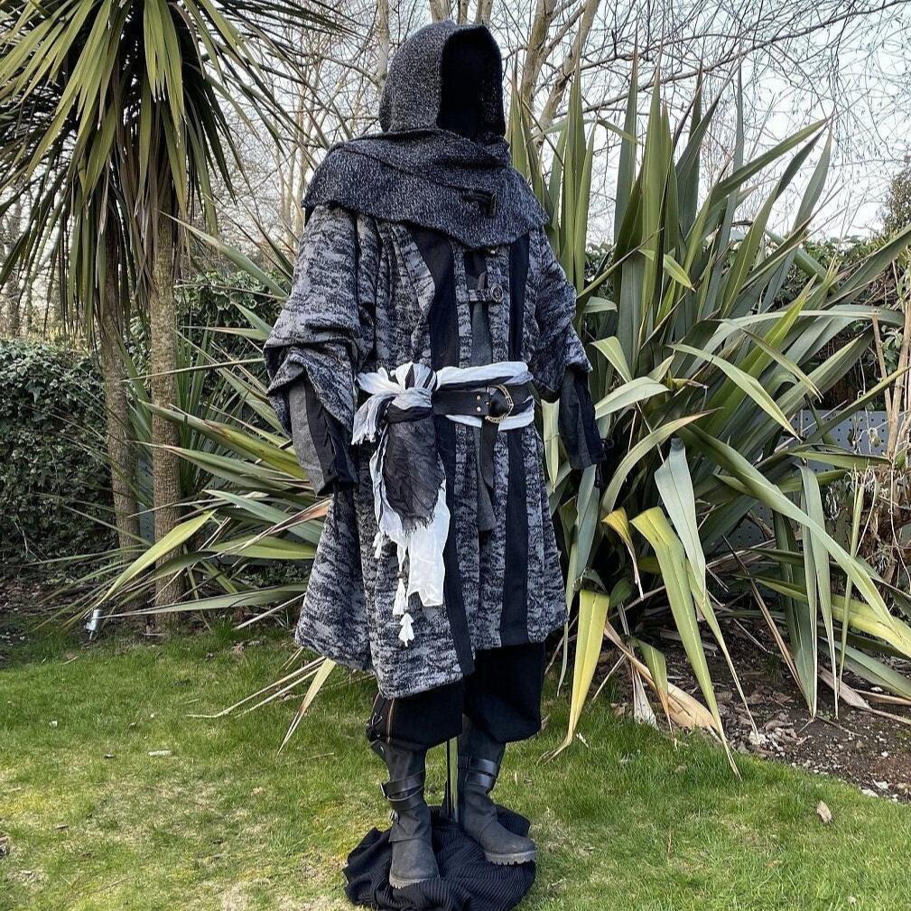 Medieval LARP costume side view, featuring grey and black hooded robe, wool hood, shirt and trousers. For Renaissance Faire and historical roleplay events.