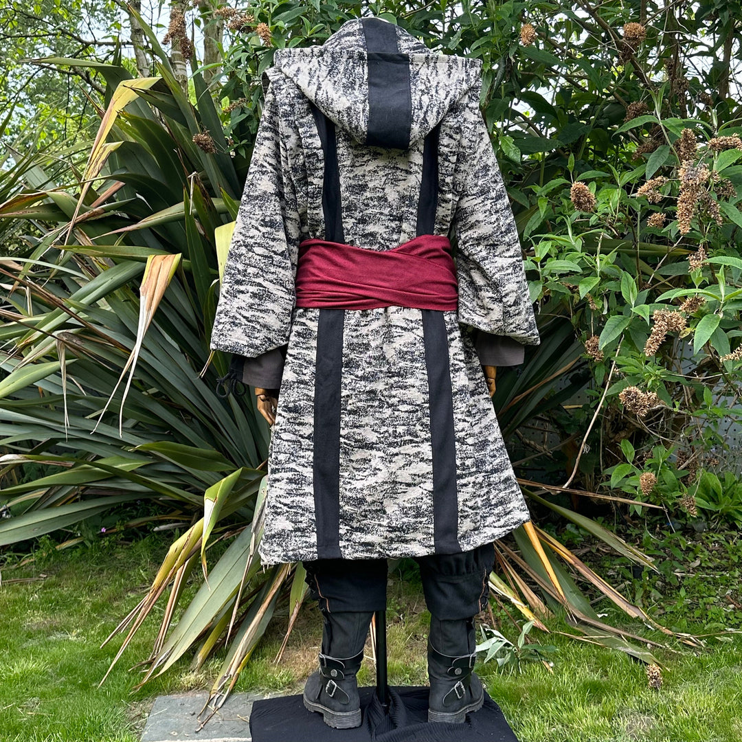 Medieval LARP costume back view, featuring brown and black hooded robe, two-tone shirt, trousers and sash. For Renaissance Faire and historical roleplay events.