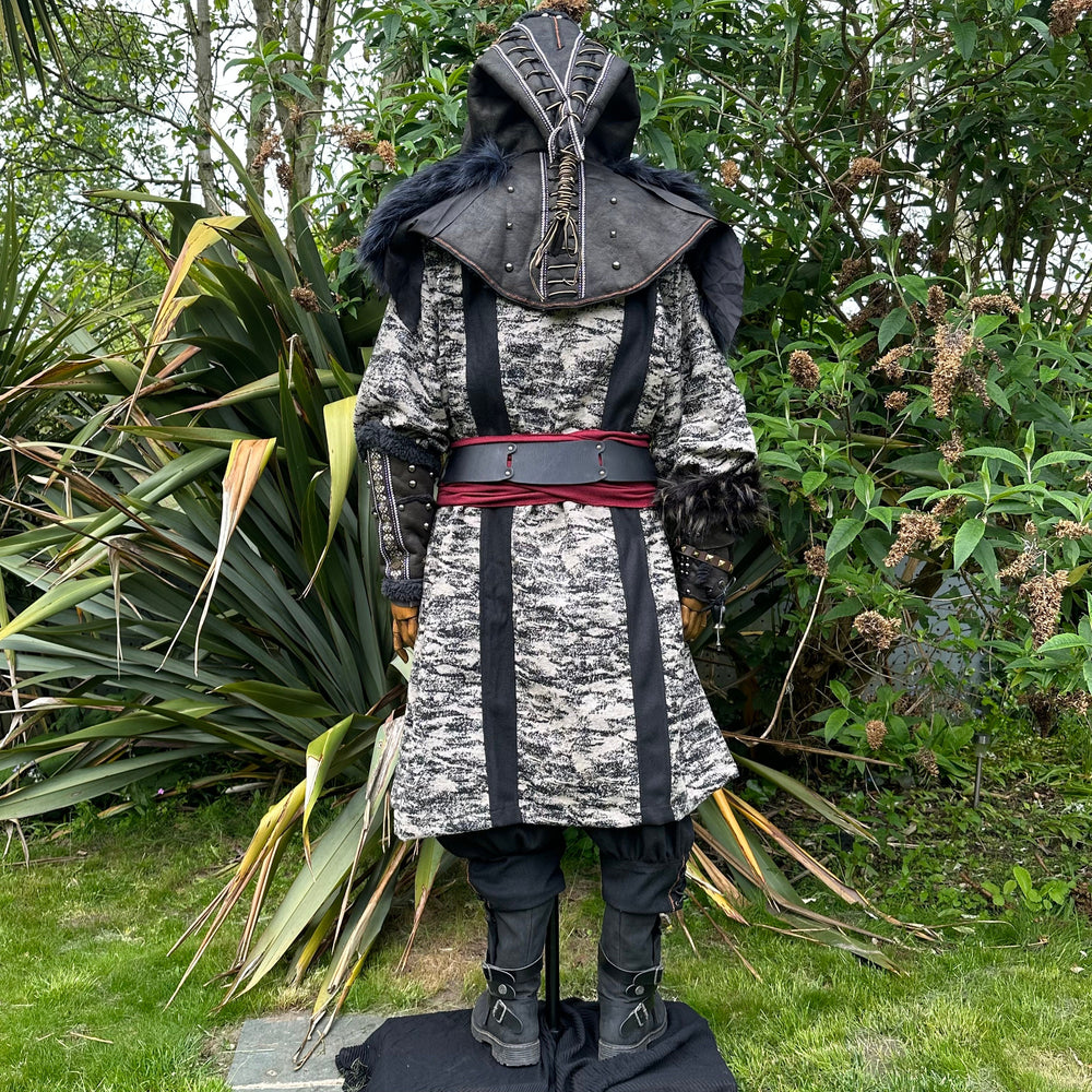Medieval LARP costume back view, featuring faux leather hood and vambraces, brown hooded robe, shirt, trousers, belt and sash. For Renaissance Faire and historical roleplay events.