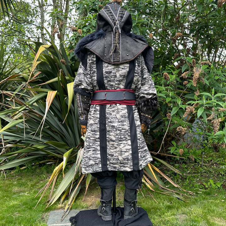 Medieval LARP costume back view, featuring faux leather hood and vambraces, brown hooded robe, shirt, trousers, belt and sash. For Renaissance Faire and historical roleplay events.