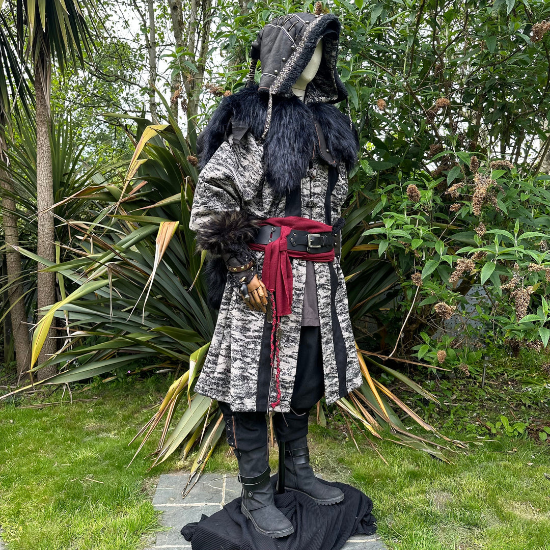 Medieval LARP costume side view, featuring faux leather hood and vambraces, brown hooded robe, shirt, trousers, belt and sash. For Renaissance Faire and historical roleplay events.