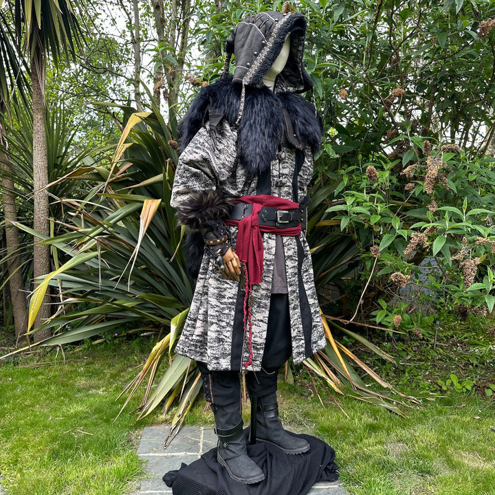 Medieval LARP costume side view, featuring faux leather hood and vambraces, brown hooded robe, shirt, trousers, belt and sash. For Renaissance Faire and historical roleplay events.