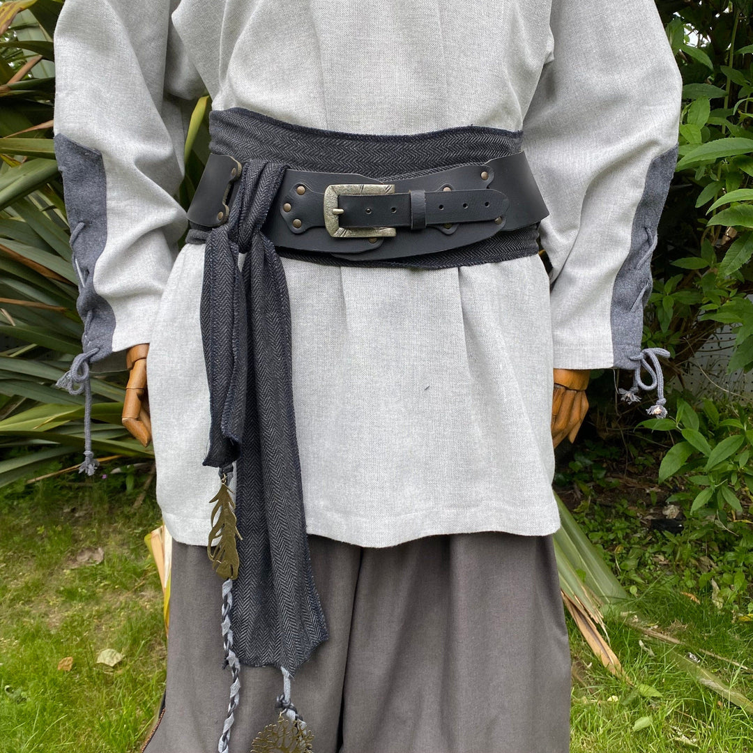 A LARP Belt and Costume Sash Set. The LARP Belt is made from Buffalo Leather in Black. The Viking Sash is a Black & Grey Herringbone Wool sash that works well by itself, or underneath the LARP Belt. The Medieval Sash has a decorated metal accessories that adds to your LARP Character, Cosplay, or Ren Faire event.