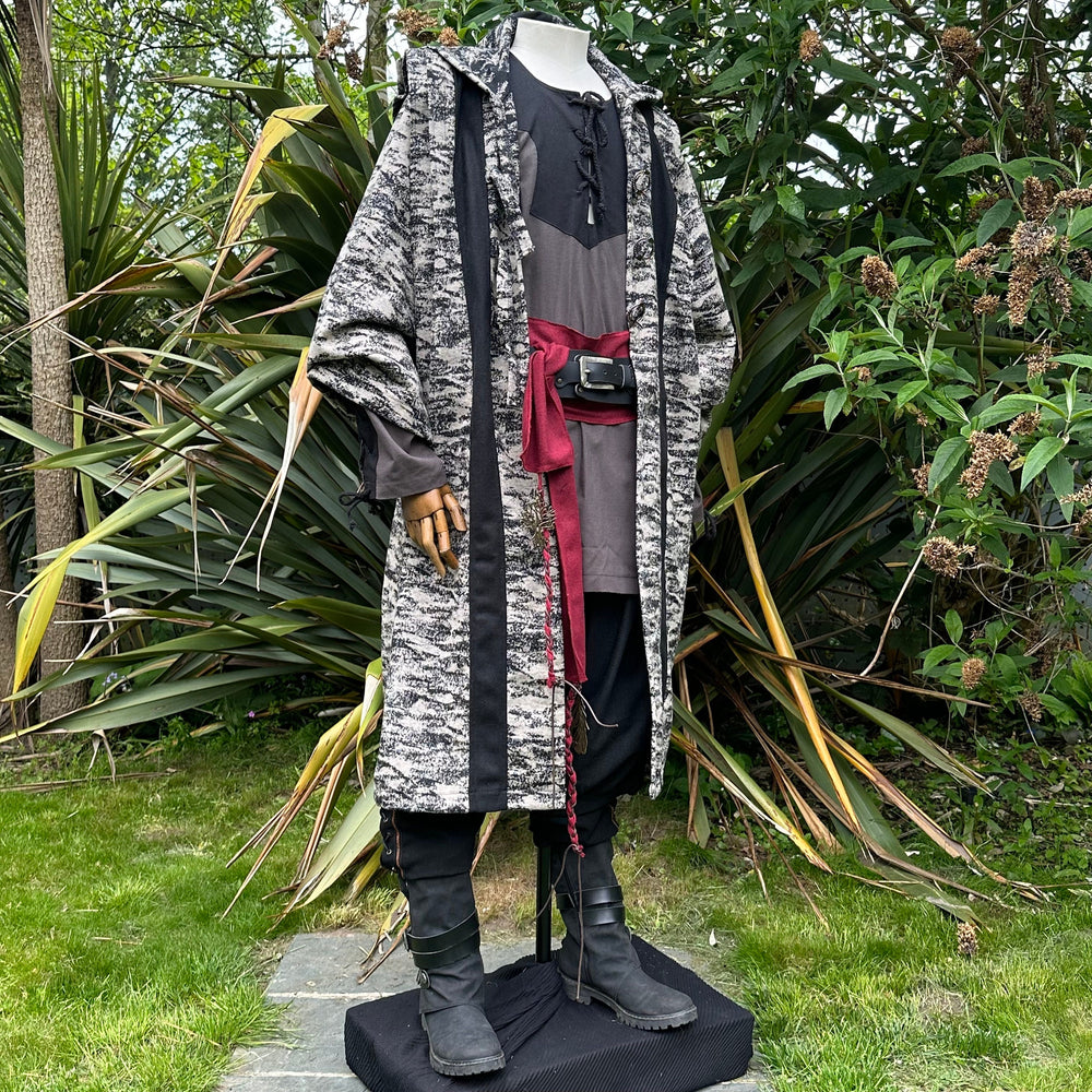 Angled front view of two-tone beige and black LARP robe, medieval fantasy cosplay costume with hood and metal clasp.