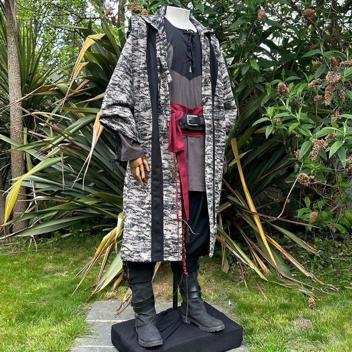 Medieval LARP costume side view, featuring brown and black hooded robe, two-tone shirt, trousers and sash. For Renaissance Faire and historical roleplay events.