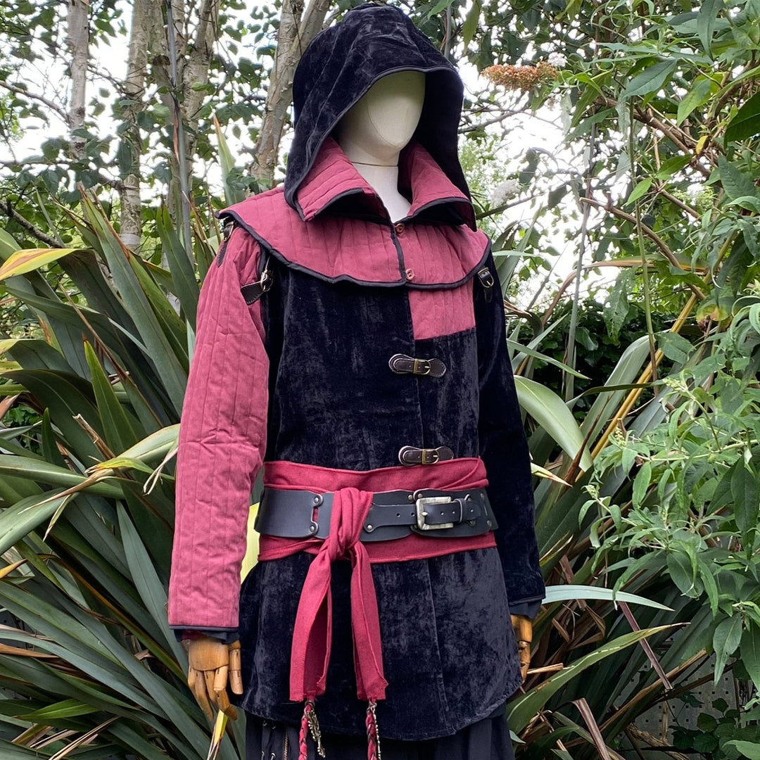 Side view of a medieval LARP costume, featuring a black and red gambeson jacket, matching snood hood, black leather belt, and red woolen sash. Medieval costume for Renaissance Faires and roleplay events.