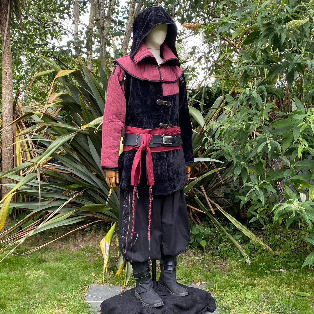 Side view of a medieval LARP costume, featuring a black and red gambeson jacket with removable sleeves, matching hood, shirt, pants, leather belt, and woolen sash. For Ren Faire and roleplay events.
