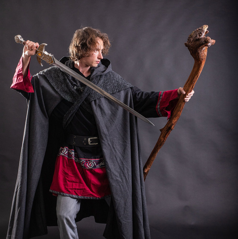 Side view of model in grey medieval LARP cloak holding staff, fantasy cosplay costume for warriors or adventurers.
