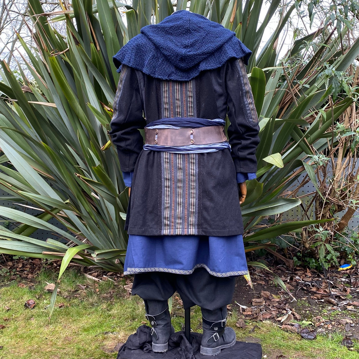 Rear view of a medieval LARP jacket with ornate striped panels and blue accents.