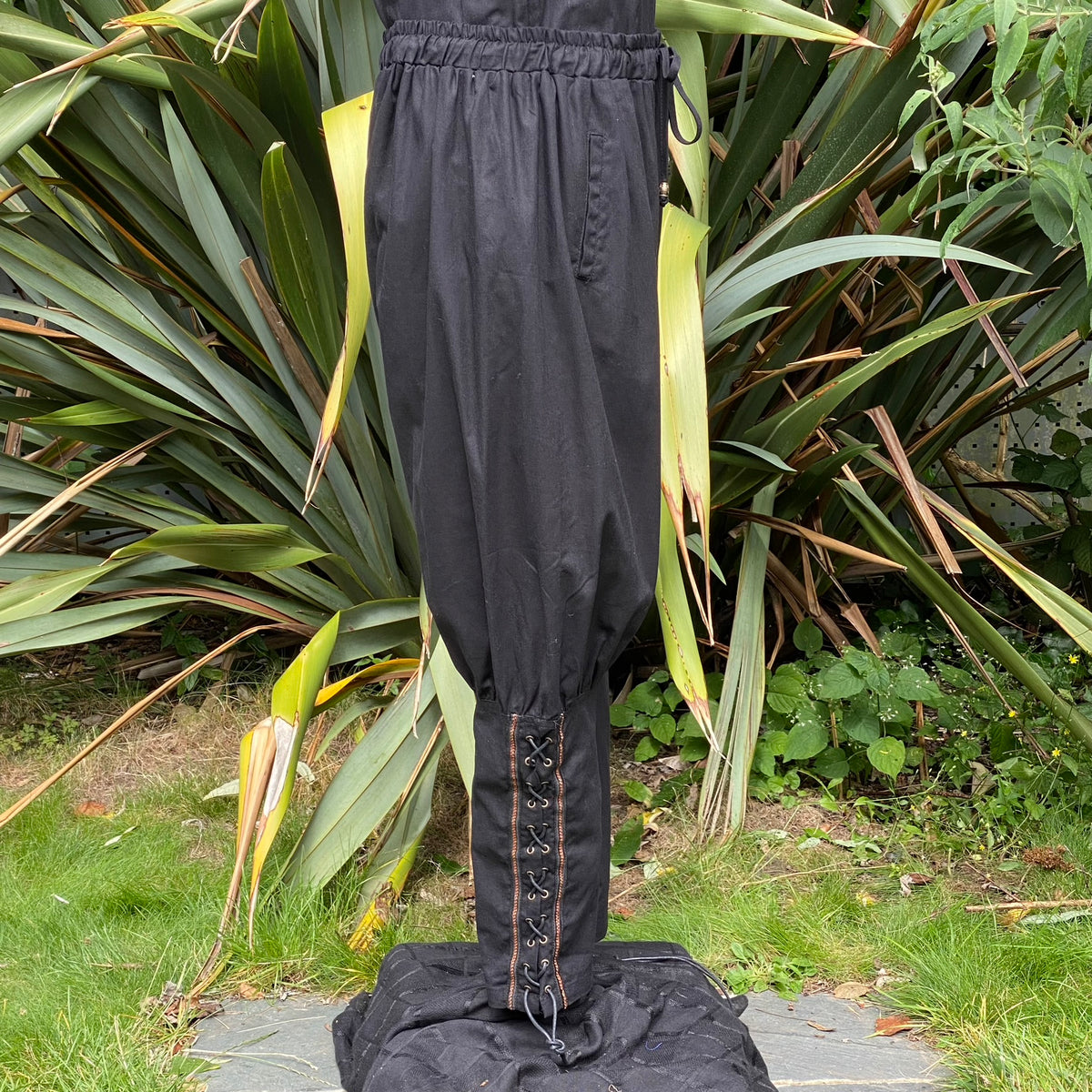 Black medieval LARP pants with lace-up details, standing.