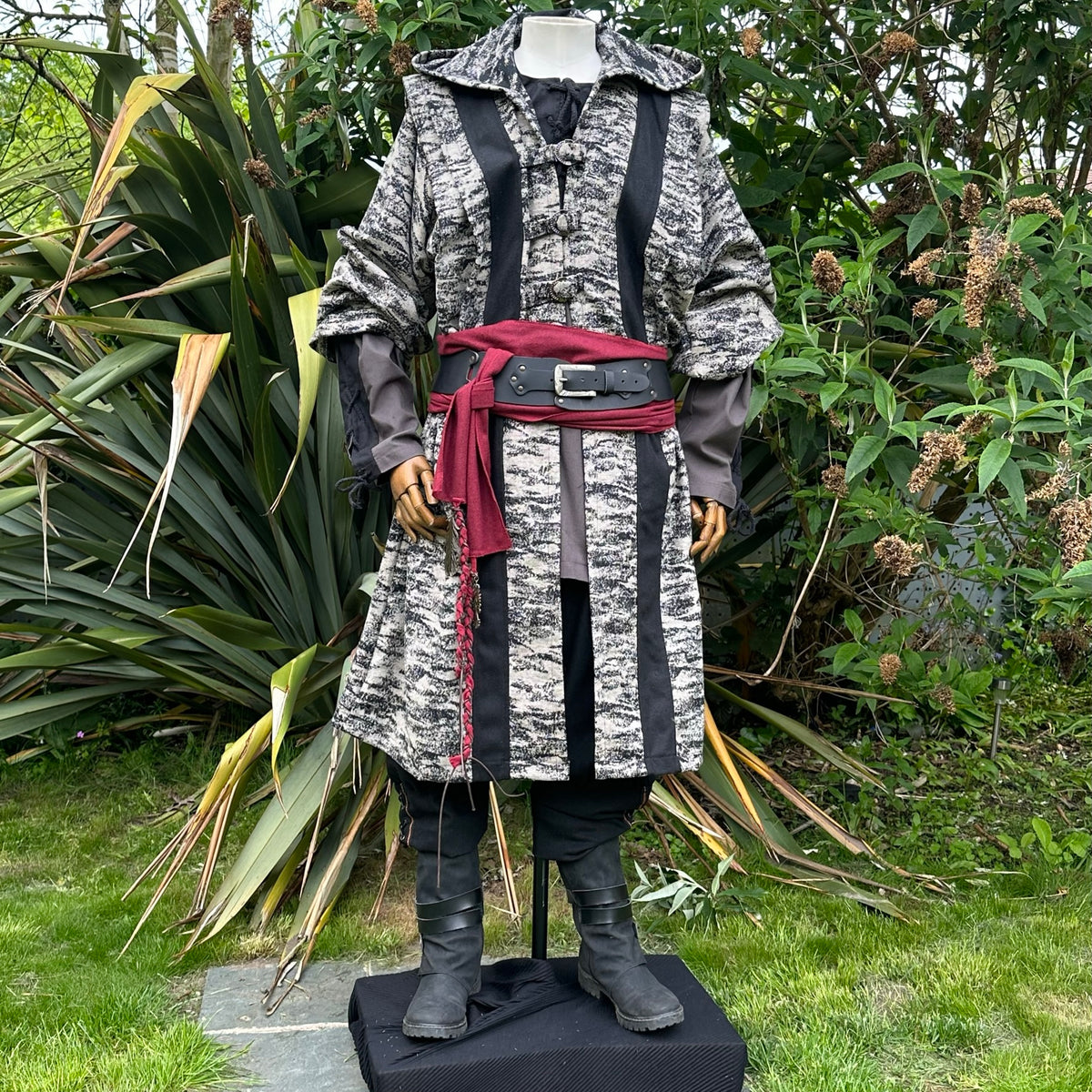 Medieval LARP robe with red belt, garden backdrop, front view.