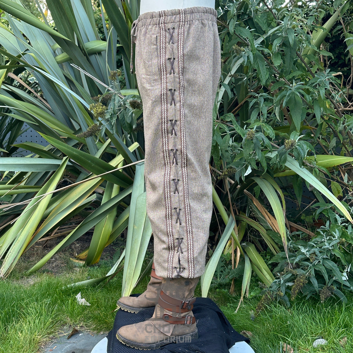 brown straight leg medieval wool trousers with decorative braiding.