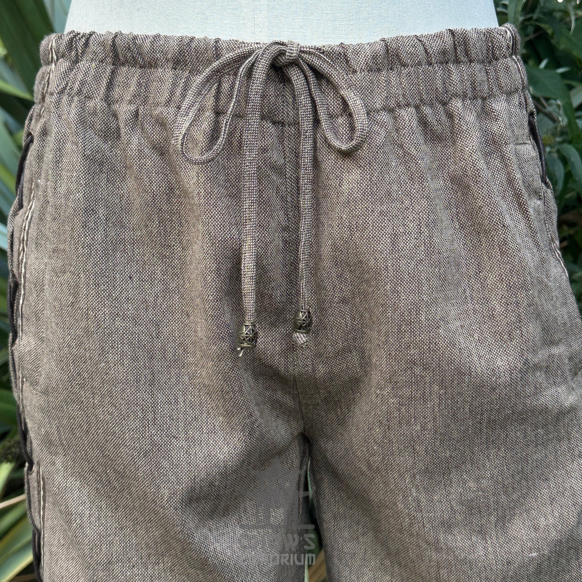close-up of brown wool medieval trousers lace and braid trim.