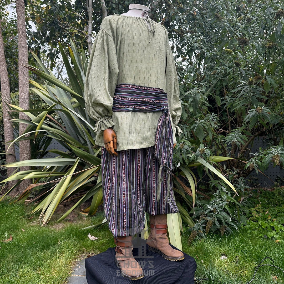 Medieval LARP outfit side view, featuring a green shirt, striped trousers and sash. For Renaissance Faire and historical roleplay events.