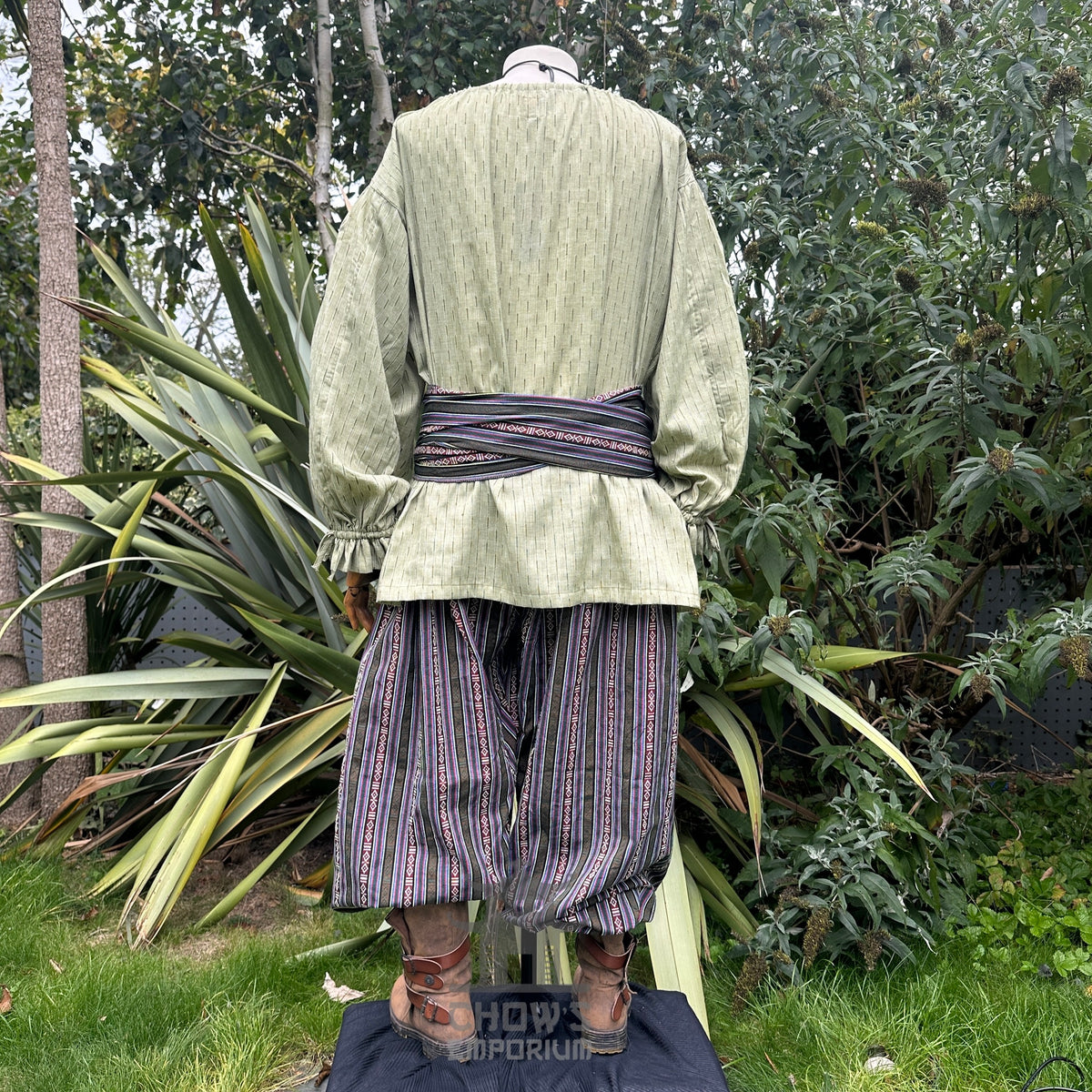 Medieval LARP outfit back view, featuring a green shirt, striped trousers and sash.