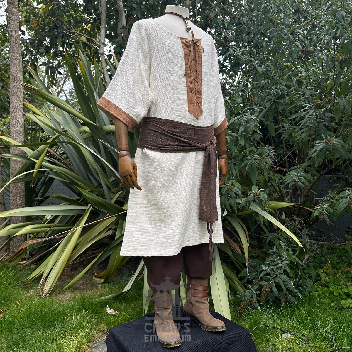 Medieval LARP outfit side view, featuring a white and brown shirt, trousers, and sash.