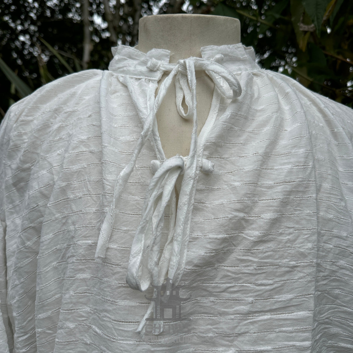 Close-up of white LARP medieval shirt on mannequin, textured fabric and tie neck.
