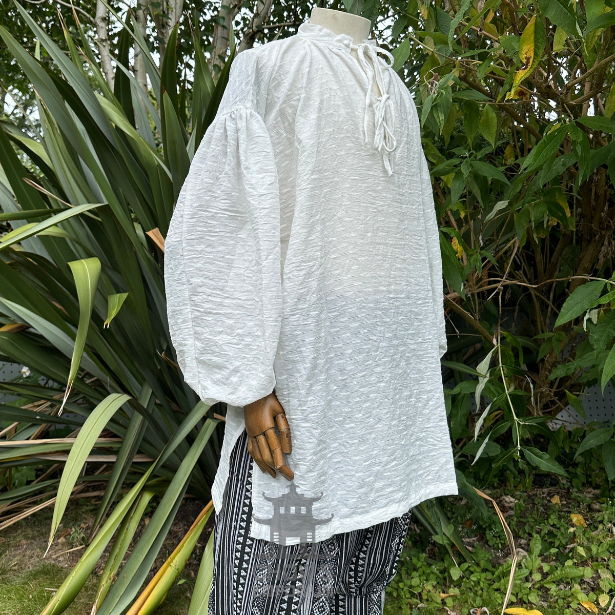 Side view of medieval LARP shirt in garden, crinkled fabric, wooden hand.