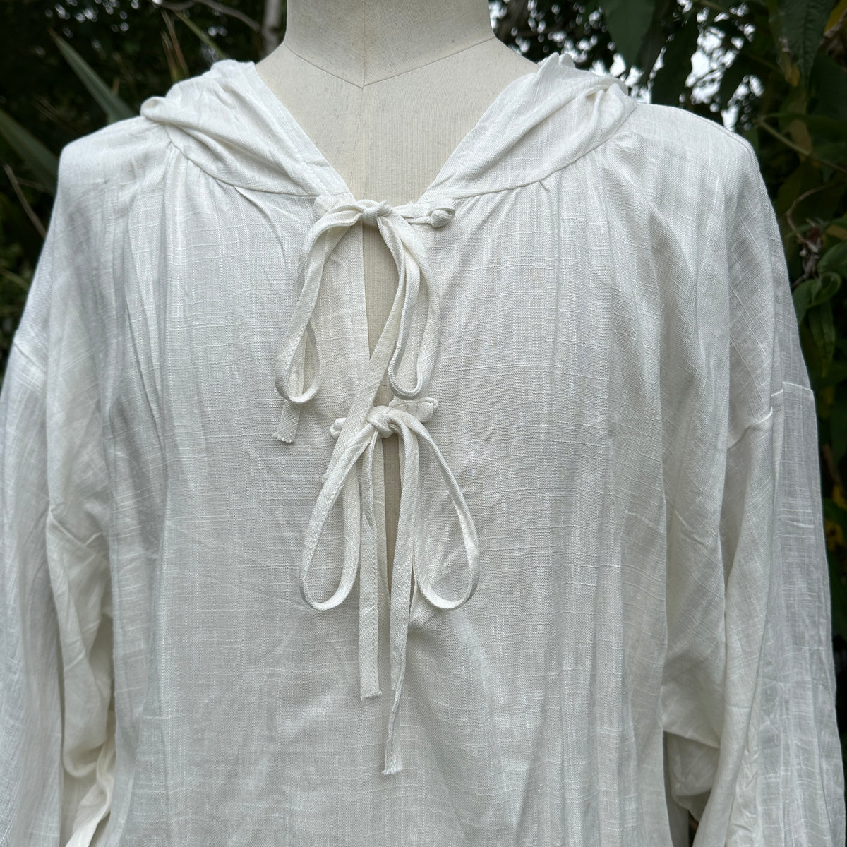 White cotton linen hooded medieval shirt with front ties, close-up view.