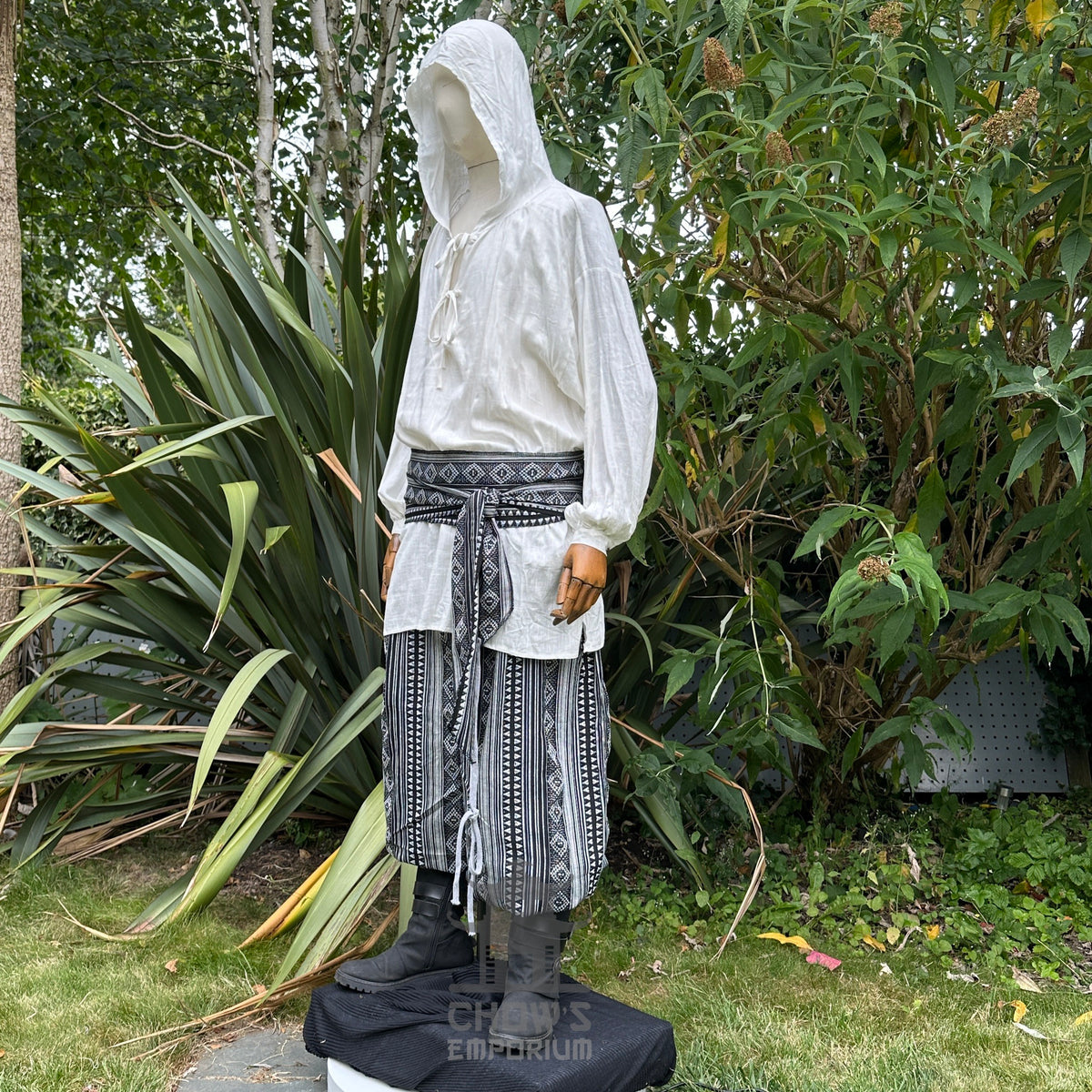 Medieval LARP outfit side view, featuring a white hooded shirt, black and white trousers and sash.