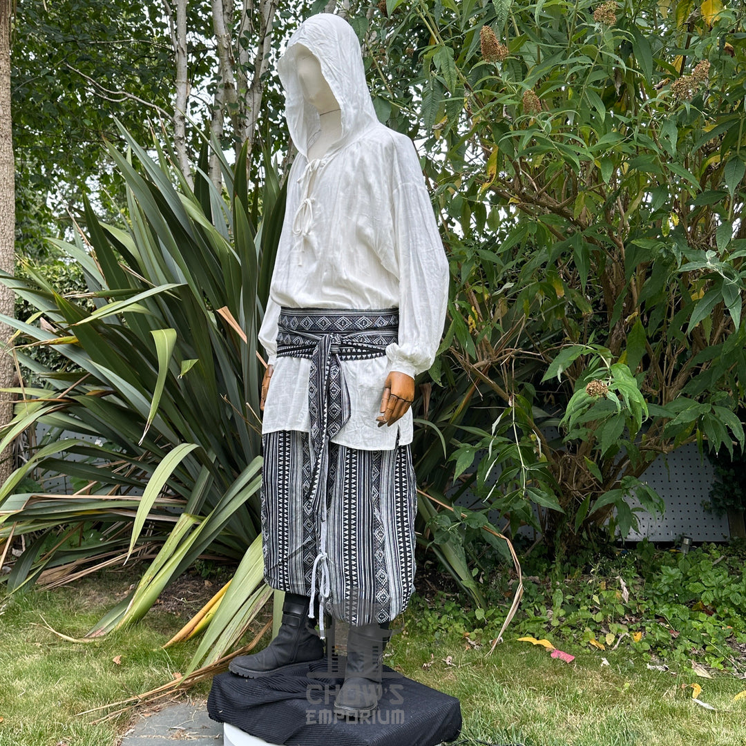 Medieval LARP outfit side view, featuring a white hooded shirt, black and white trousers and sash. For Renaissance Faire and historical roleplay events.