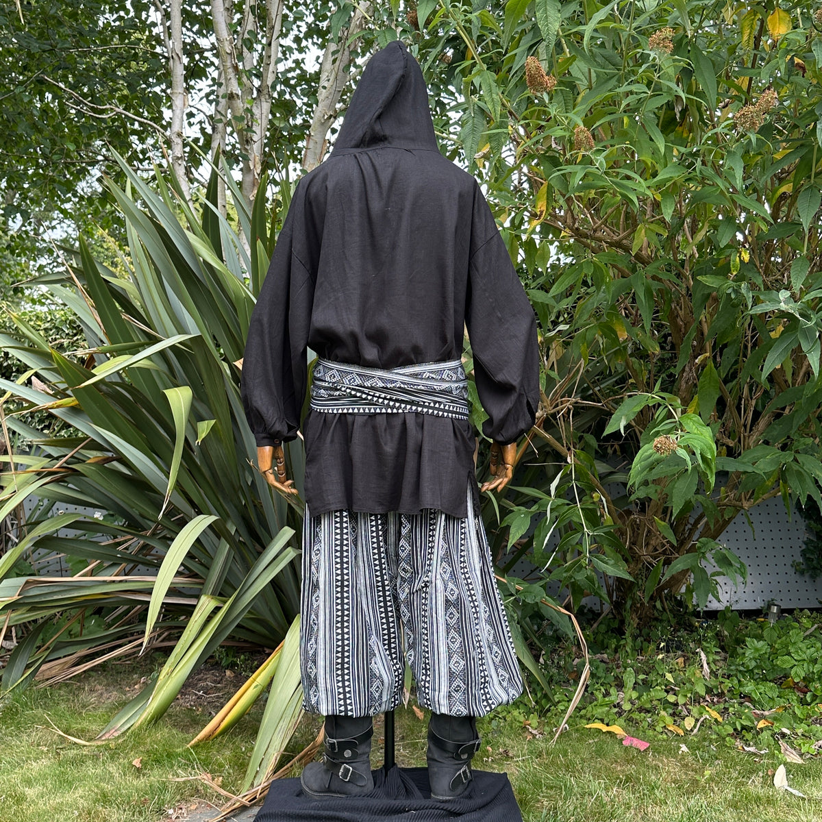 Medieval LARP outfit back view, featuring a black hooded shirt, black and white trousers and.