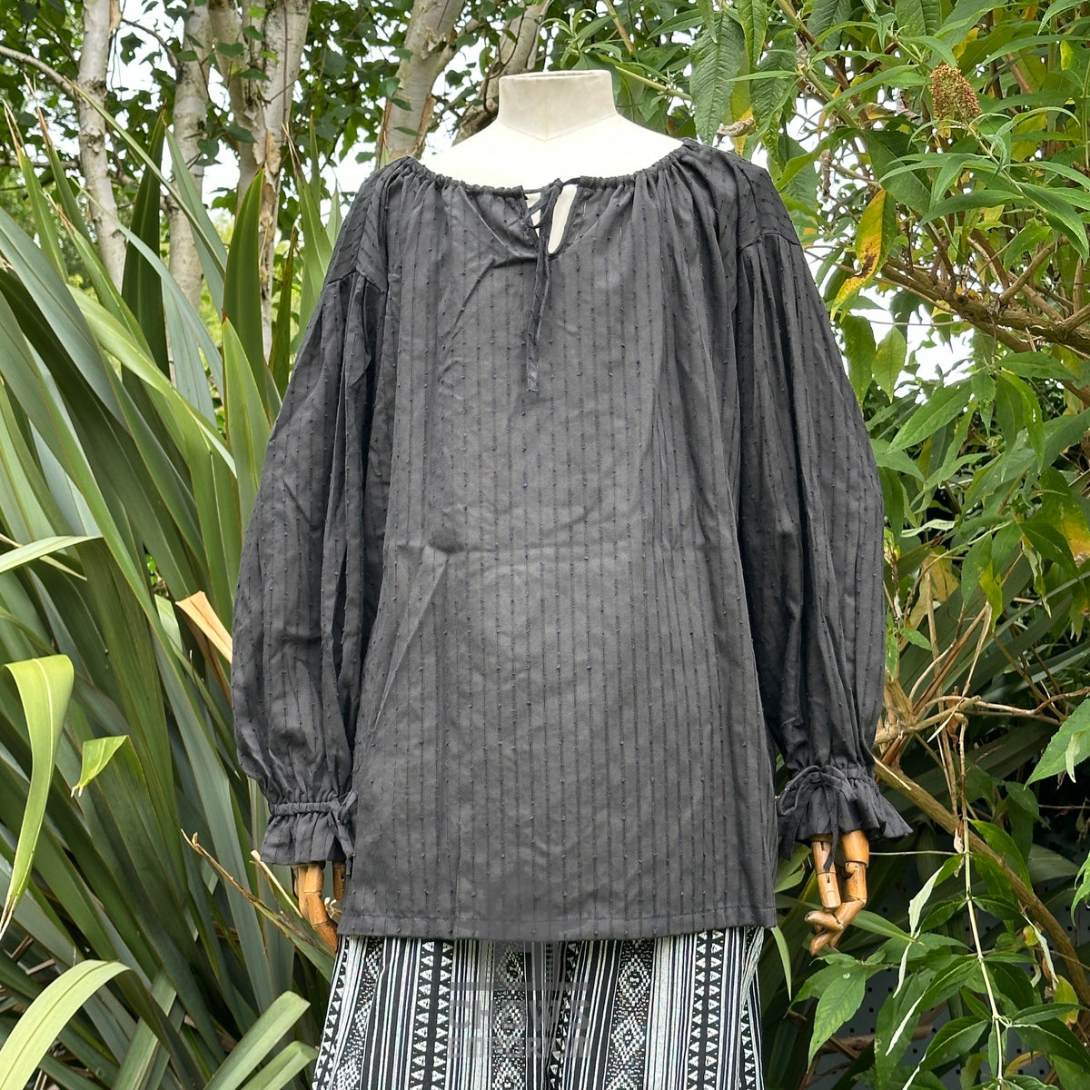Black medieval shirt with long sleeves, vertical texture, displayed outside.