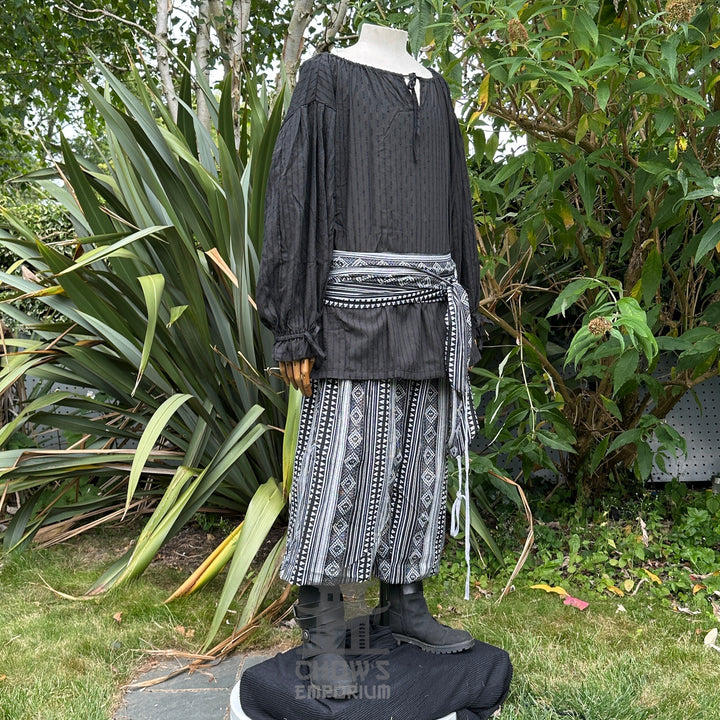Medieval LARP outfit side view, featuring a black shirt, patterned trousers and sash. For Renaissance Faire and historical roleplay events.