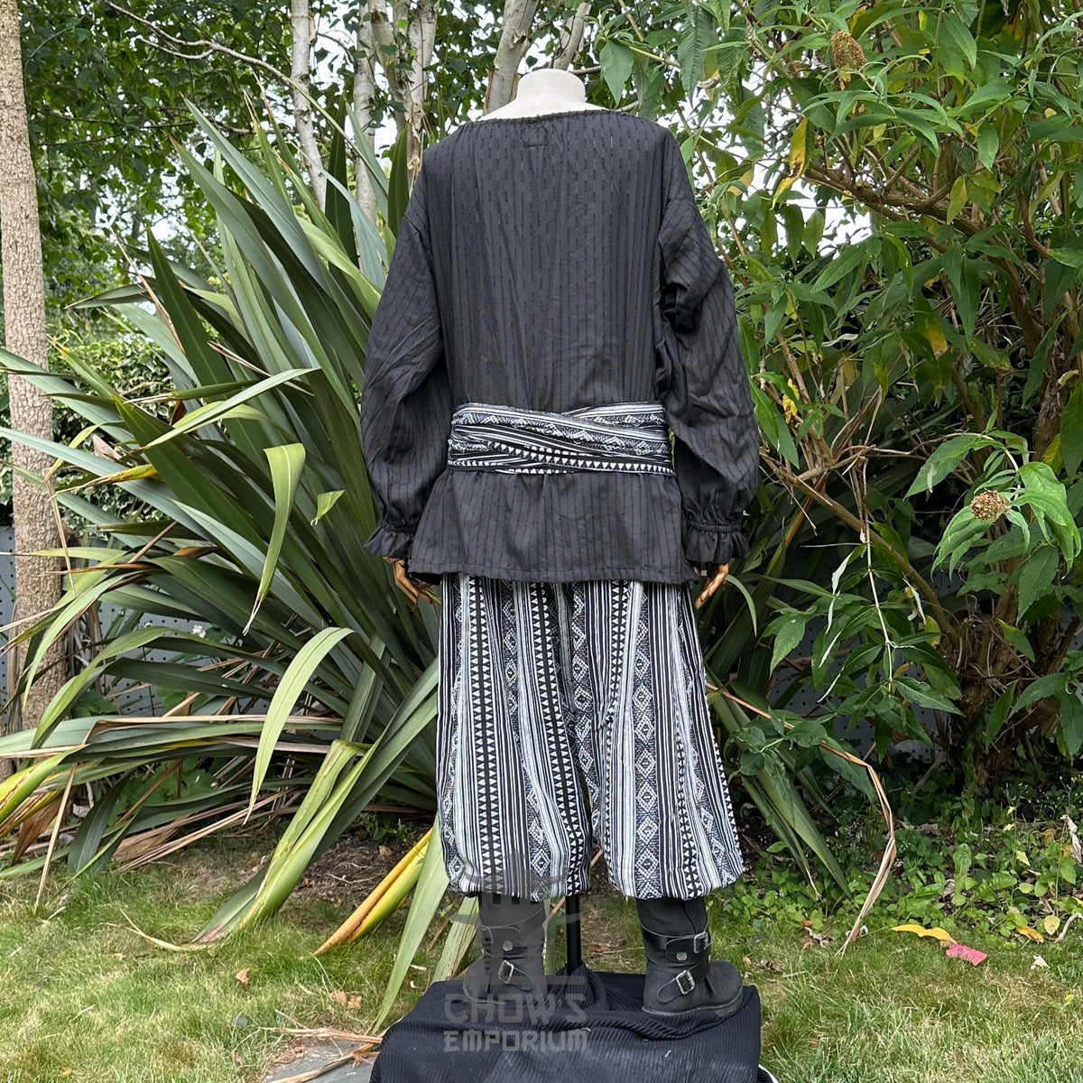 Medieval LARP outfit back view, featuring a black shirt, patterned trousers and sash.