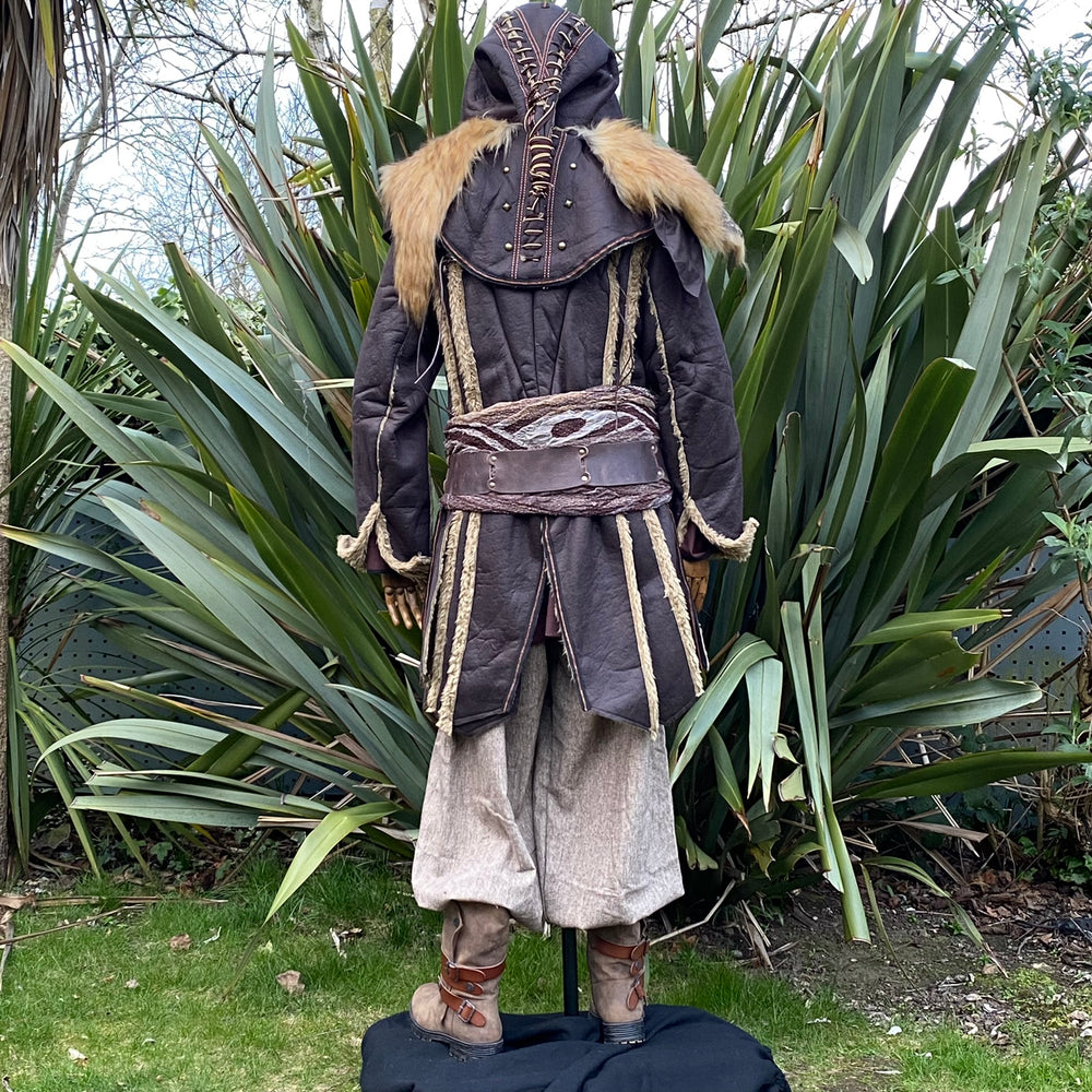 Medieval LARP costume back view featuring a brown faux leather jacket, hood and vambraces, shirt and trousers. For Renaissance Faire and historical roleplay events.