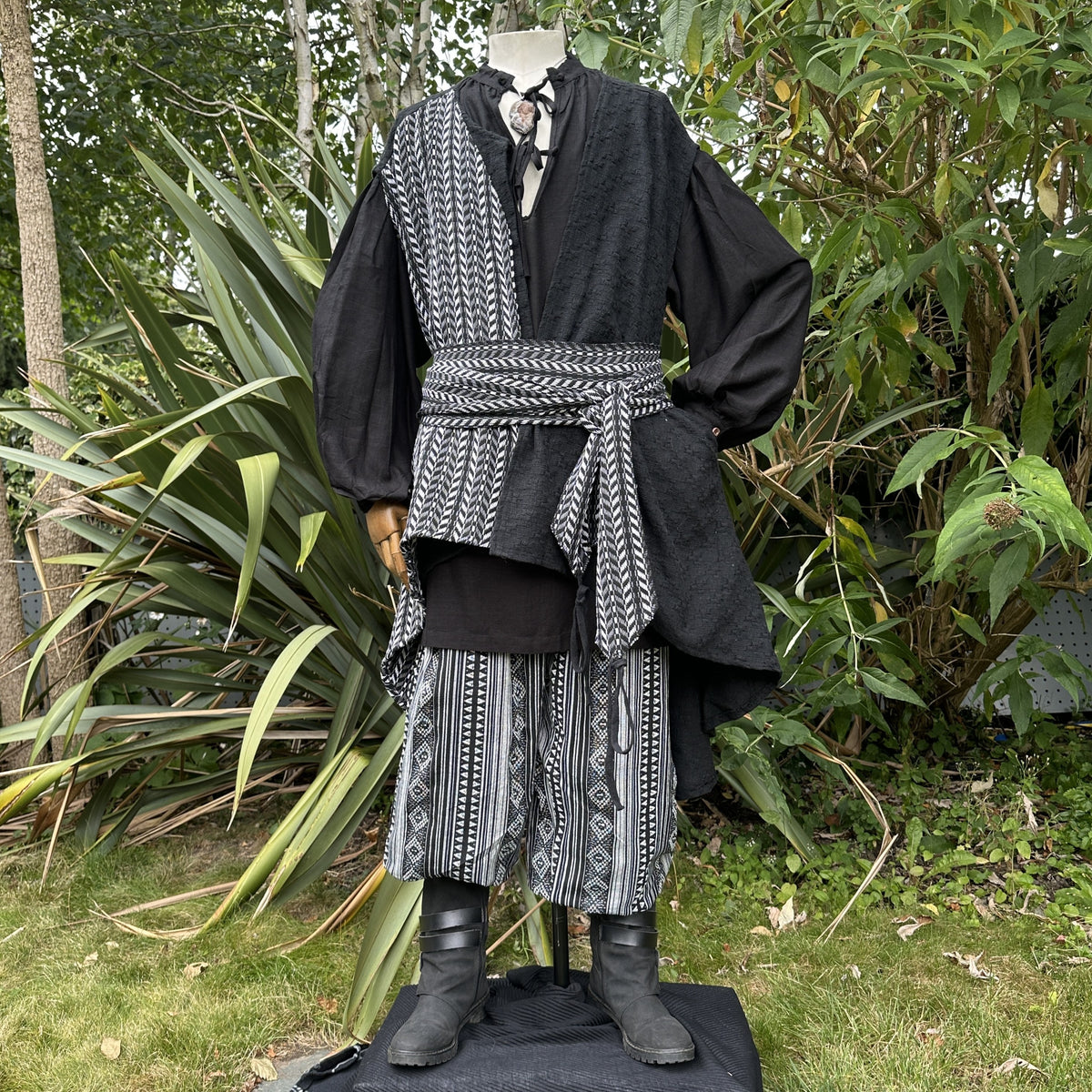 Black and grey medieval LARP outfit with patterned sash, front view.