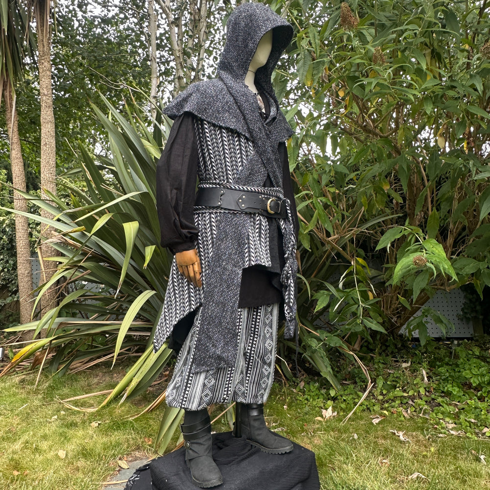Medieval LARP costume side view, includes black and white waistcoat with asymmetrical front panel and matching sash, wool hood, shirt, and trousers for Ren Faire and roleplay events.